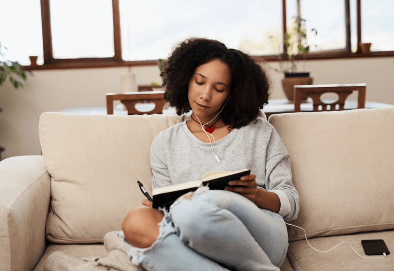 Person journaling and reflecting on personal success criteria while sitting on a couch